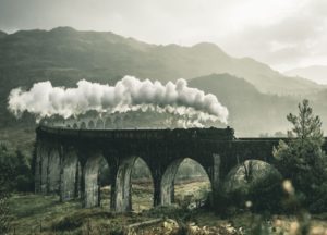 black train on railway bridge under heavy clouds