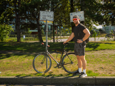 man standing beside his bicycle on a grassy knoll